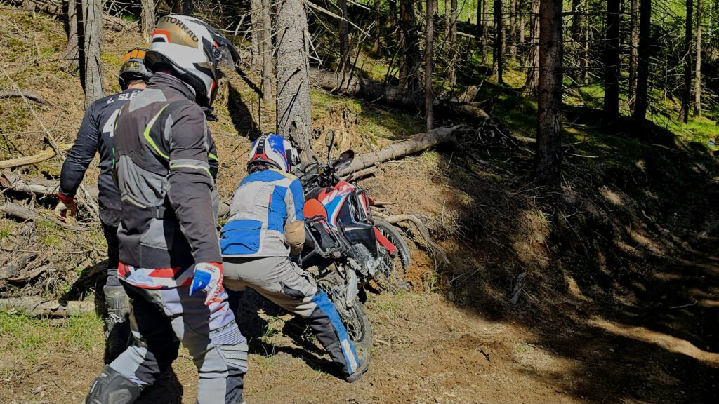 Deltakere hjelper til med å hente opp motorsykkel som har kjørt ut i skogen under offroad-trening./ Adventureskolen / Speed Motorcenter / Kjørekurs MC / Motorsykkel