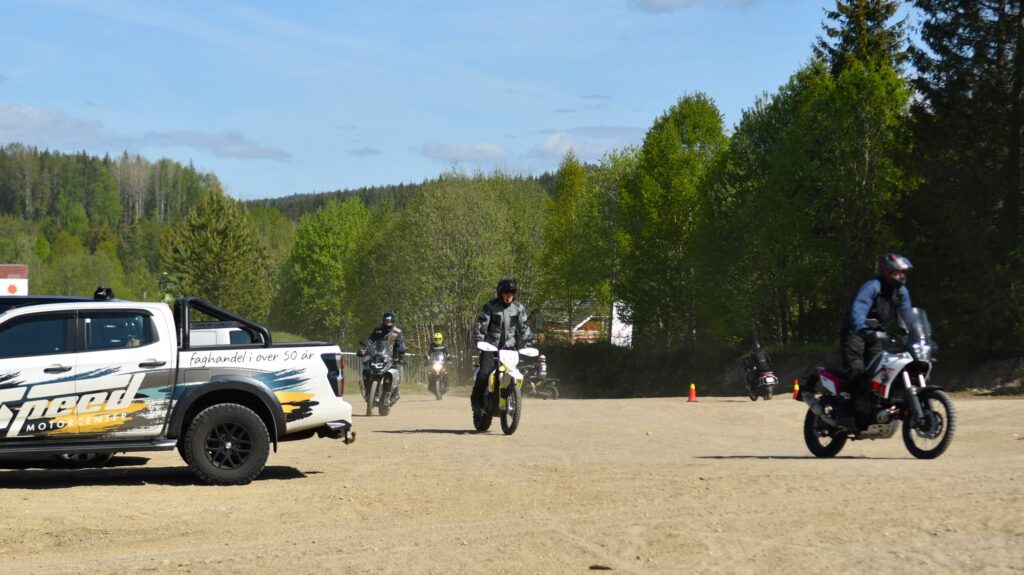 Motorsyklister ankommer grusbanen på Flittig – Speed Motorcenter sin pickup i forgrunnen./ Adventureskolen / Speed Motorcenter / Kjørekurs MC / Motorsykkel