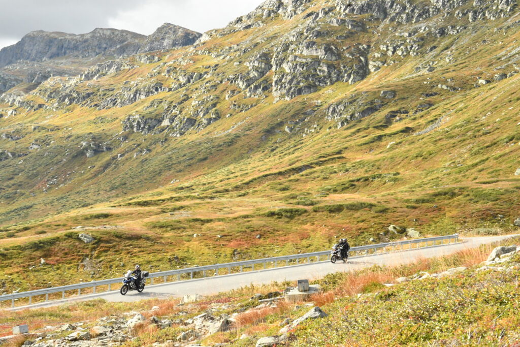 To motorsyklister kjører langs veien med høstfargede fjell som bakteppe på Beitostølen i september. – Speed Motorcenter, Touringtreffet, Speed MC, Beitostølen, MC